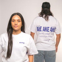 Two people wearing white t-shirts with blue Maori text, one facing forward and the other facing backward.