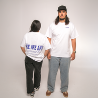 Two people wearing white t-shirts with Maori text, standing against a plain background