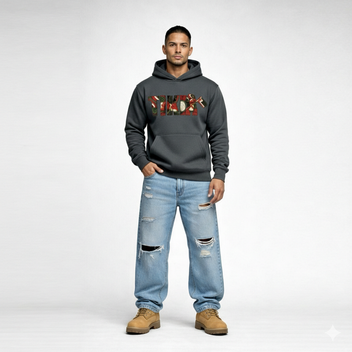 Male model wearing Cravass Tiki hoodie in charcoal grey with Māori-inspired TIKI woven graphic, streetwear fit, front view