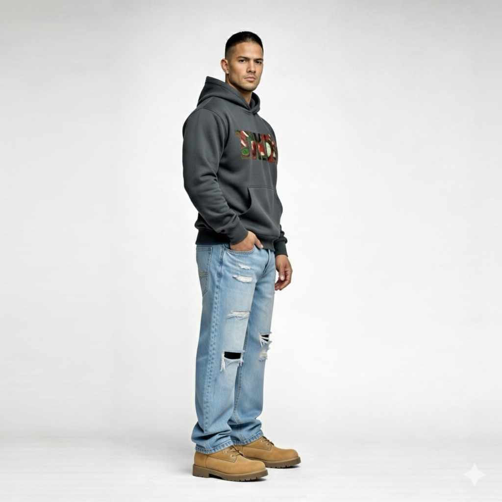 Side view of male model wearing Cravass Tiki hoodie in charcoal grey with Māori TIKI graphic, modern streetwear style