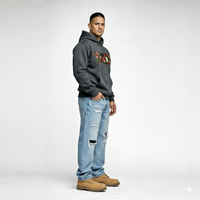 Side view of male model wearing Cravass Tiki hoodie in charcoal grey with Māori TIKI graphic, modern streetwear style