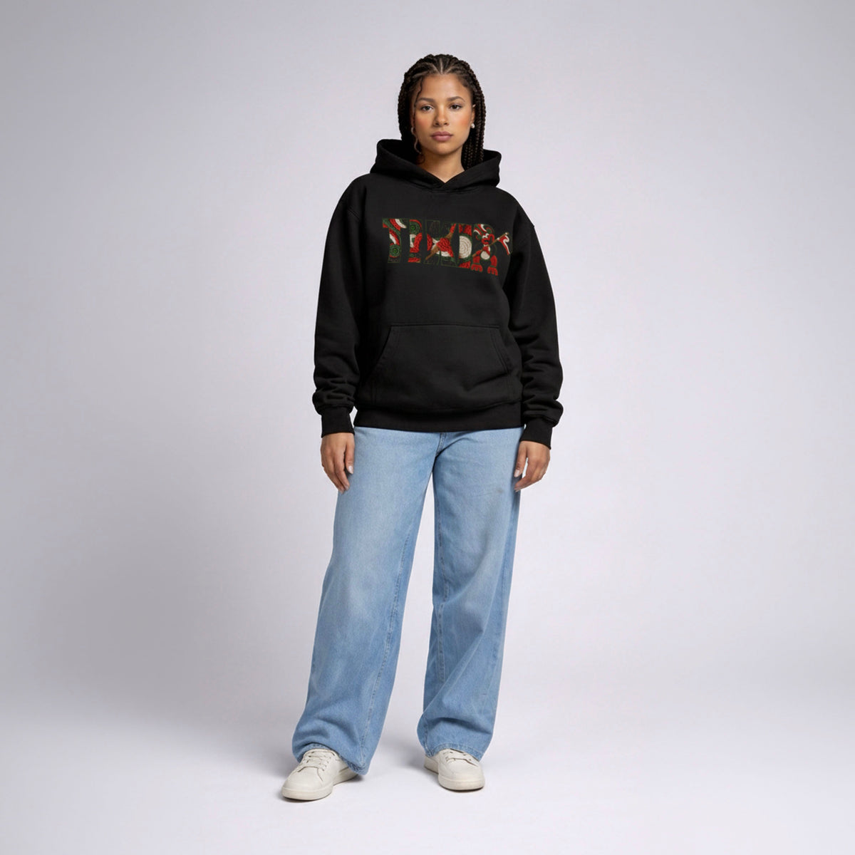 Front-facing female model in Cravass Tiki hoodie featuring Māori-inspired TIKI artwork and textured woven streetwear graphic