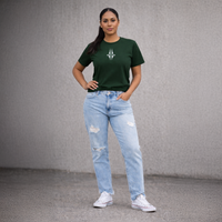 A woman wearing a green t-shirt with a logo and light blue jeans against a grey background. Streetwear by Cravass.