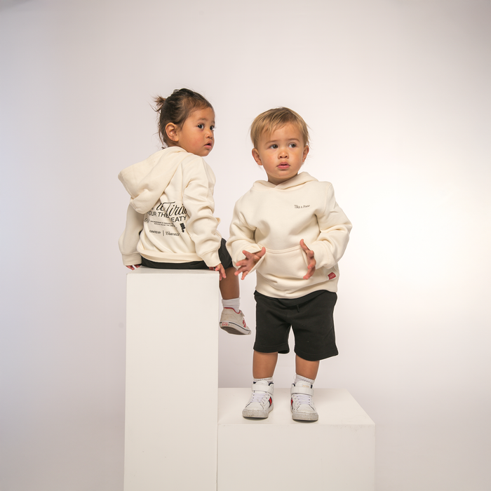Two kids modelling, Front view of Toi Tu Tiriti Kids Hoody in black, featuring 'Toitū te Tiriti' text.