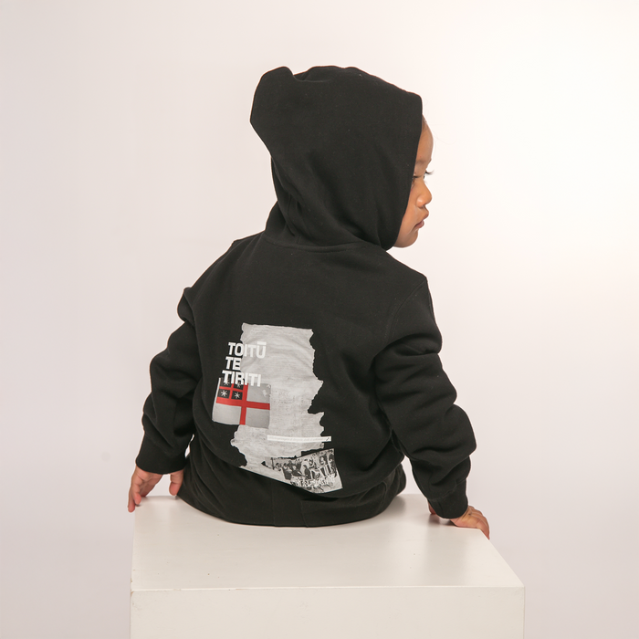 Back view of Te Kara Toi Tu Tiriti Kids Hoody in Black, showcasing the cultural design.