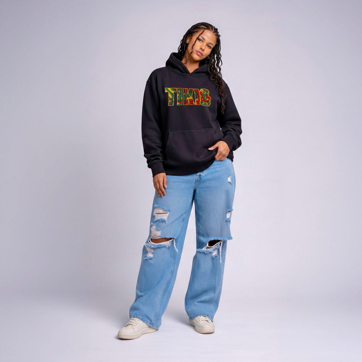 Model wearing black Cravass TIKI statement hoodie with colourful Māori-inspired graphic, streetwear fit, New Zealand design