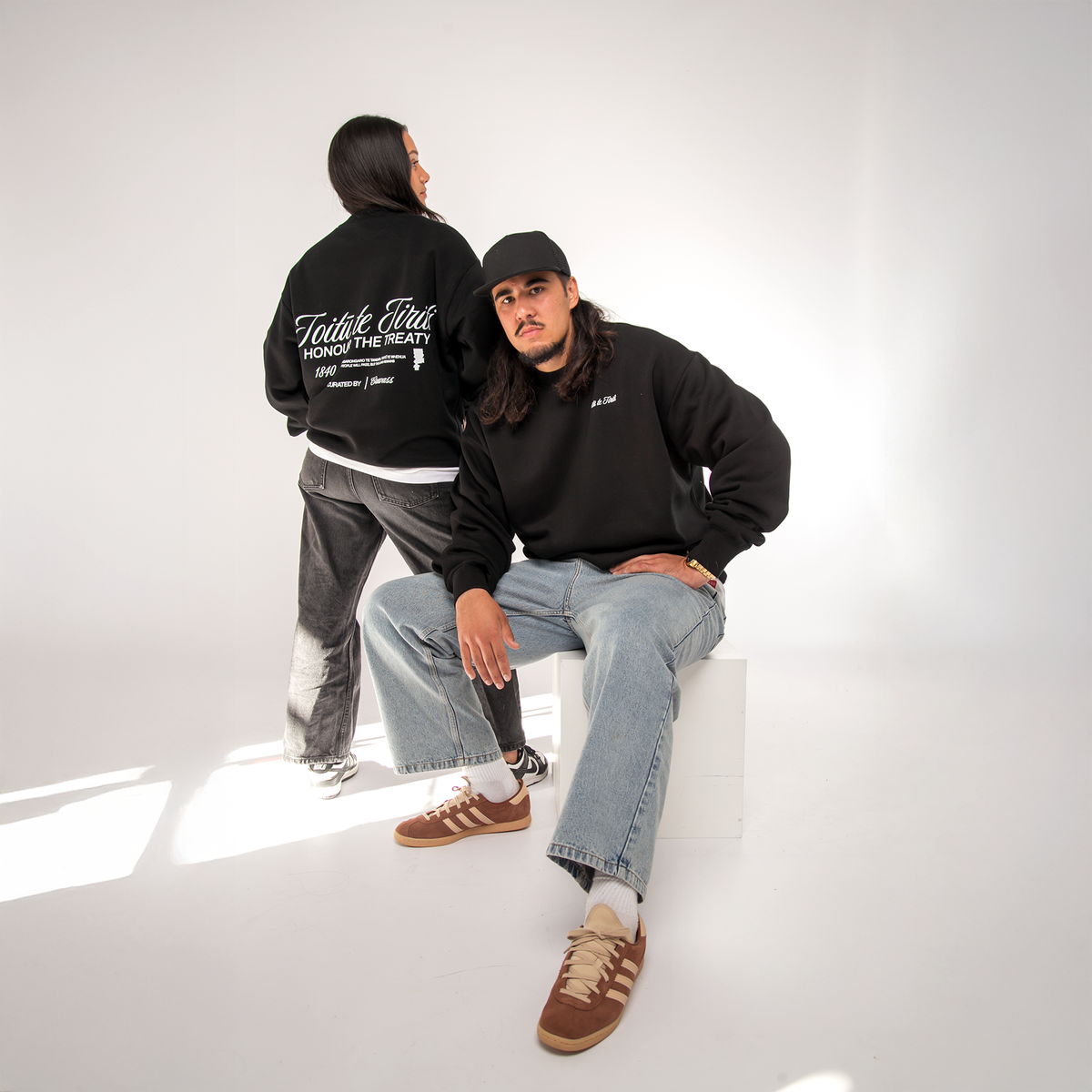 Black oversized Toitū te Tiriti Māori typography crew worn by model
