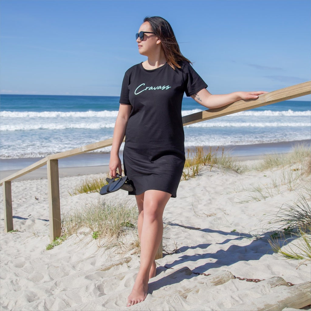 Beautiful model wearing black dress with cravass logo at the papamoa beach