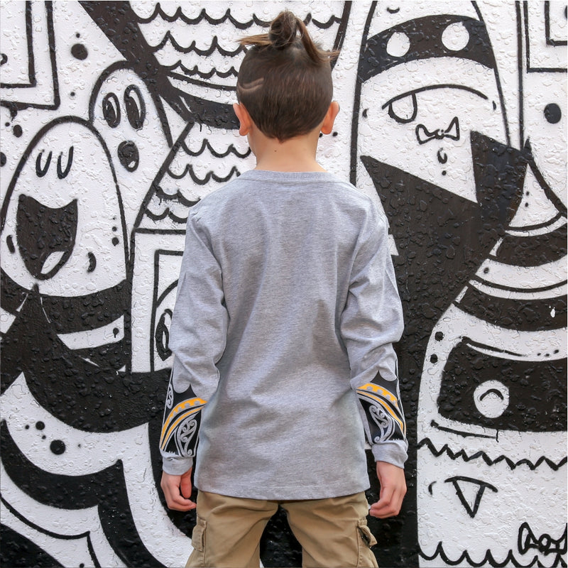 Young boy wearing cravass clothing with maori design with street art in the background. 
