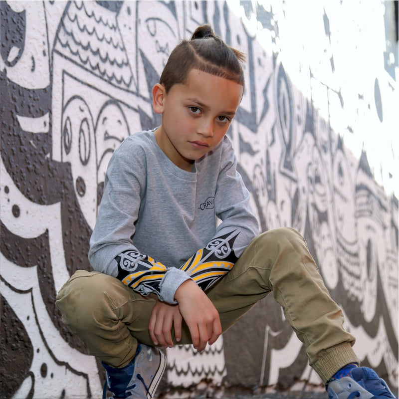 Young boy wearing cravass clothing with maori design with street art in the background. 