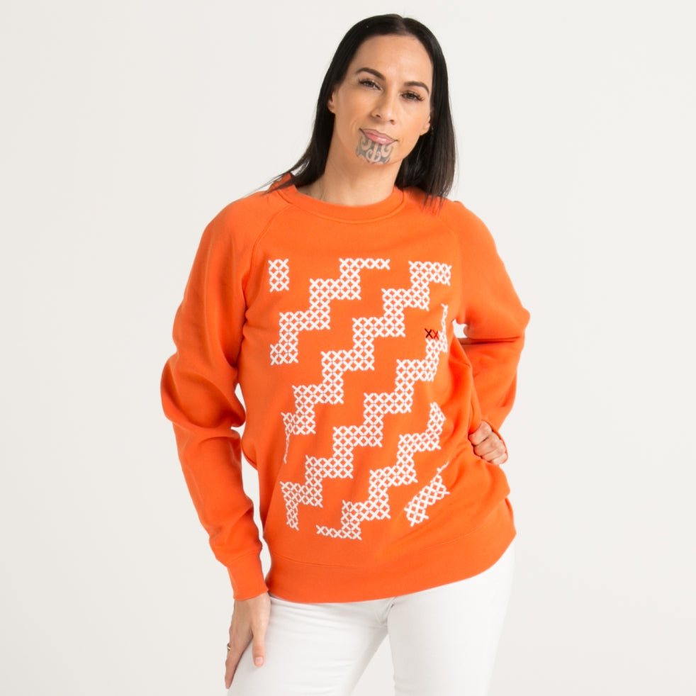 Women's orange crew jersey with white Maori poutama design from Cravass clothing