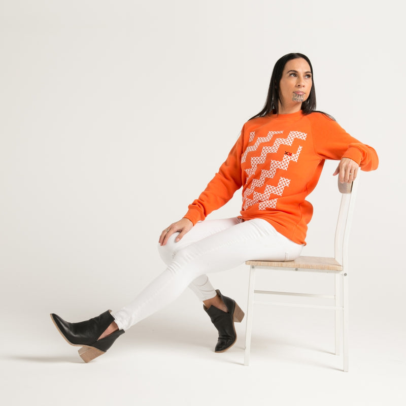 Women's orange crew jersey with white Maori poutama design from Cravass clothing