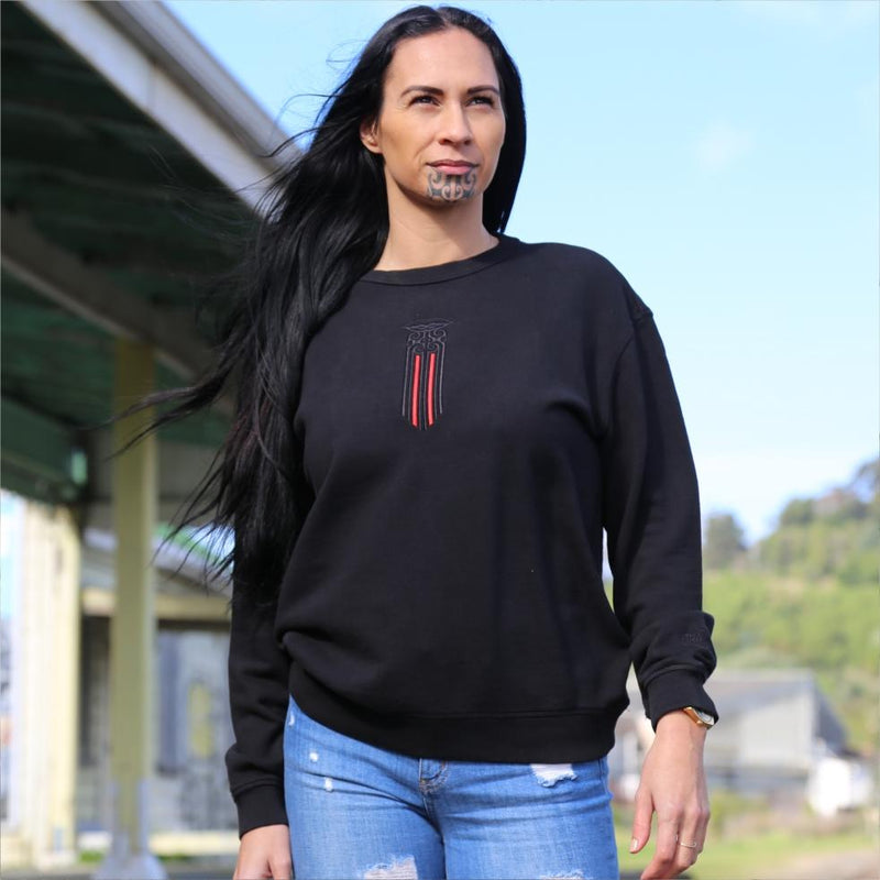 Women's black crew jersey with a black and red Maori moko kauae design. outside gisborne railway station nz