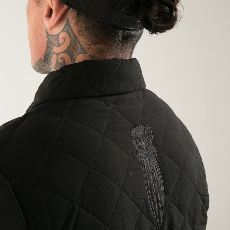 Black quilted men's jacket with embroidered Taiaha design. Original Maori design from Cravass clothing. 