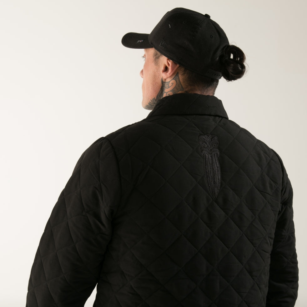 Black quilted men's jacket with embroidered Taiaha design. Original Maori design from Cravass clothing. 